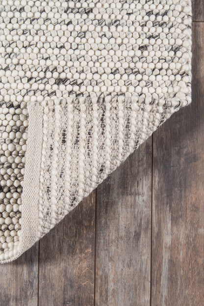 Neutral ivory boucle rug with chunky loop pile; cream and gray speckles, folded corner reveals woven underside.