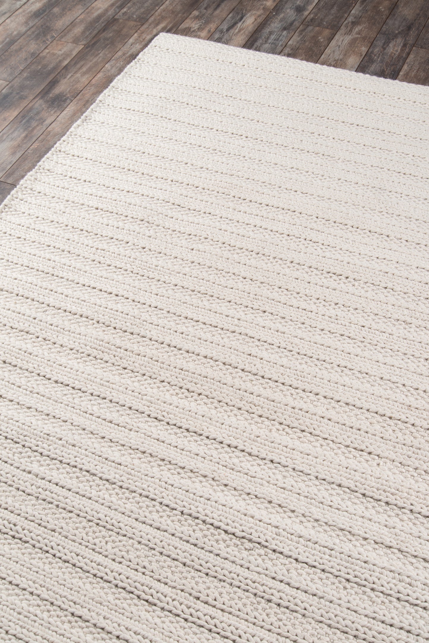 Cream woven rug with chunky loop texture on dark wood floor.