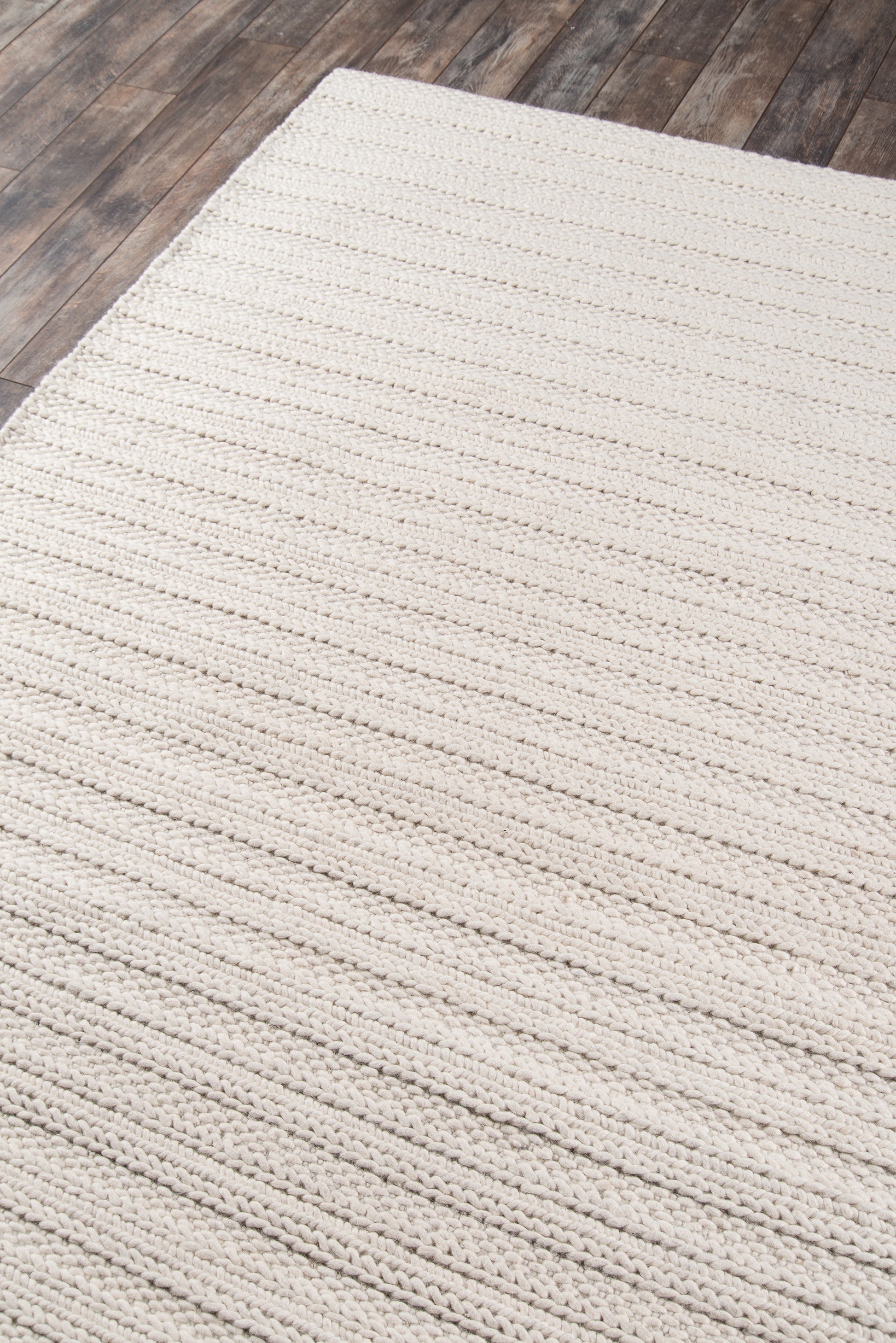 Creamy beige chunky woven rug with textured horizontal loops, rectangular, cozy living-room style on wood floor.
