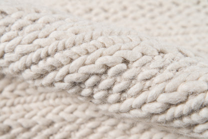 Close-up of cream chunky twisted yarn, thick wool skein with soft rope-like texture for cozy scarves or sweaters