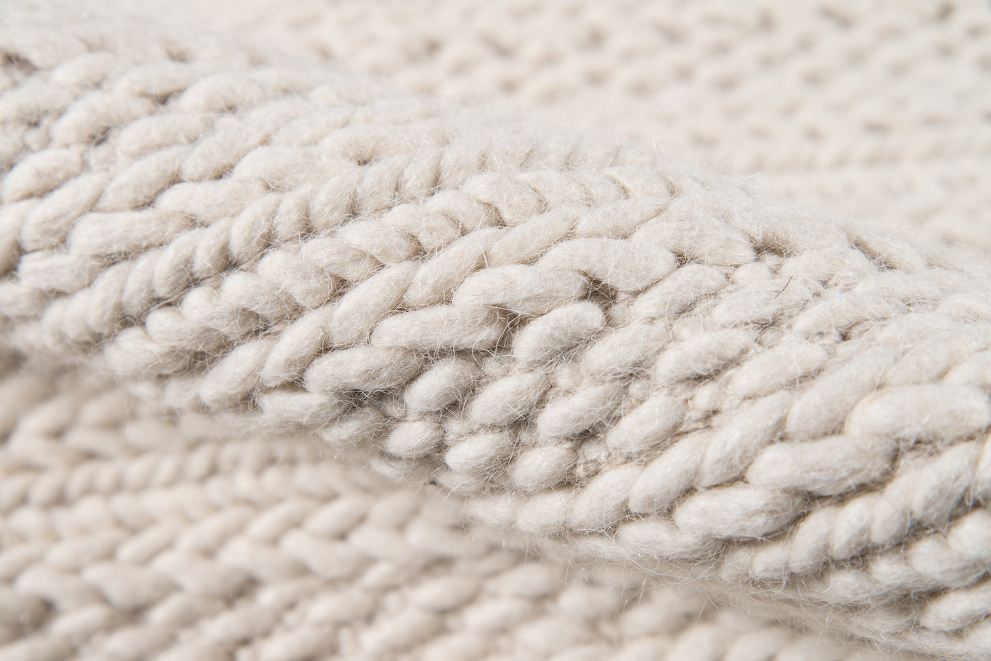 Ivory chunky knit yarn close-up with thick twisted strands, cozy wool texture for scarves or blankets.