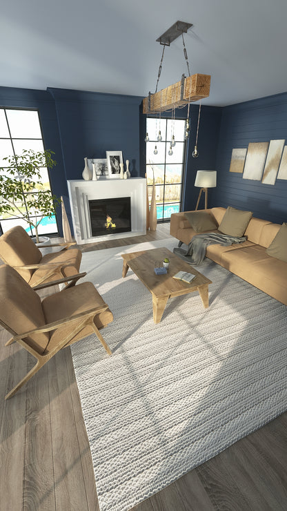 Blue living room with tan sofa and wooden chairs, coffee table, light gray textured rug, rustic beam chandelier with hanging bulbs, fireplace.