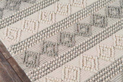 Ivory, sand and grey geometric woven area rug with diamond patterns; textured stripes, on wood floor.