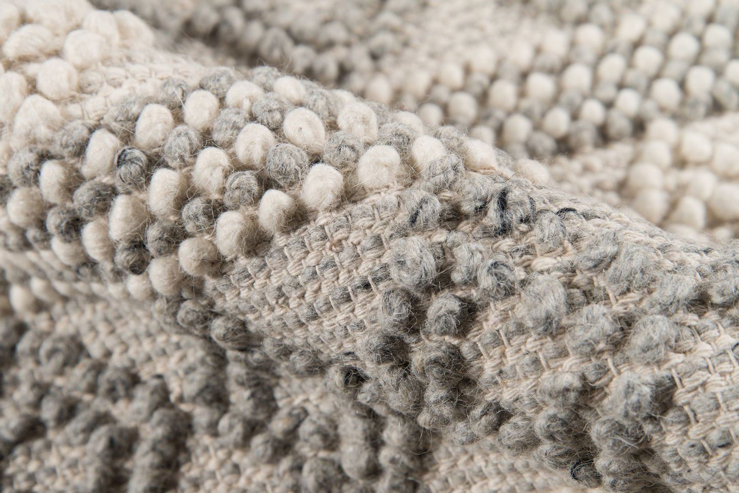 Close-up of a chunky boucle knit throw blanket in ivory and gray with soft looped texture.
