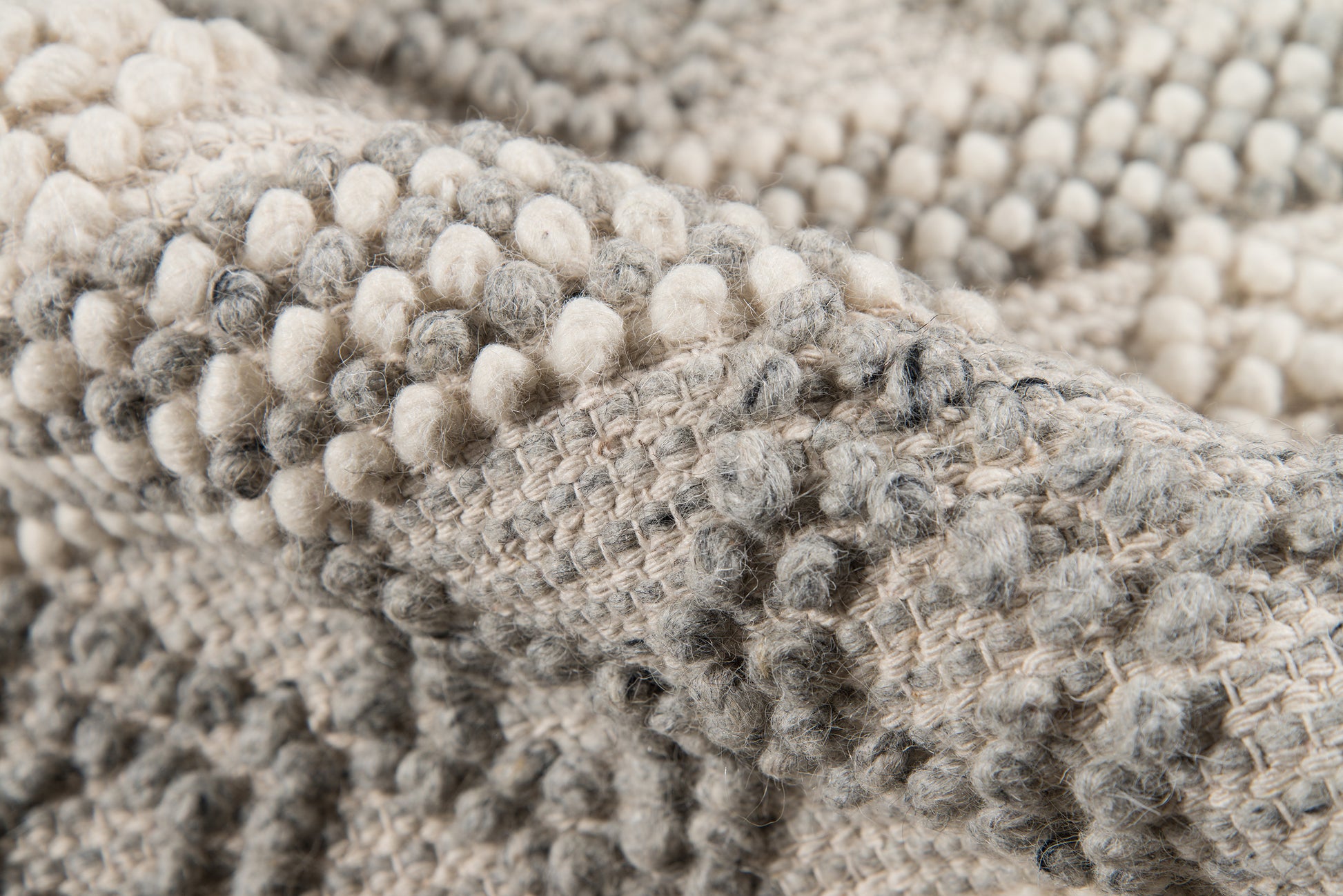 Close-up of a chunky boucle knit throw blanket in ivory and gray with soft looped texture.