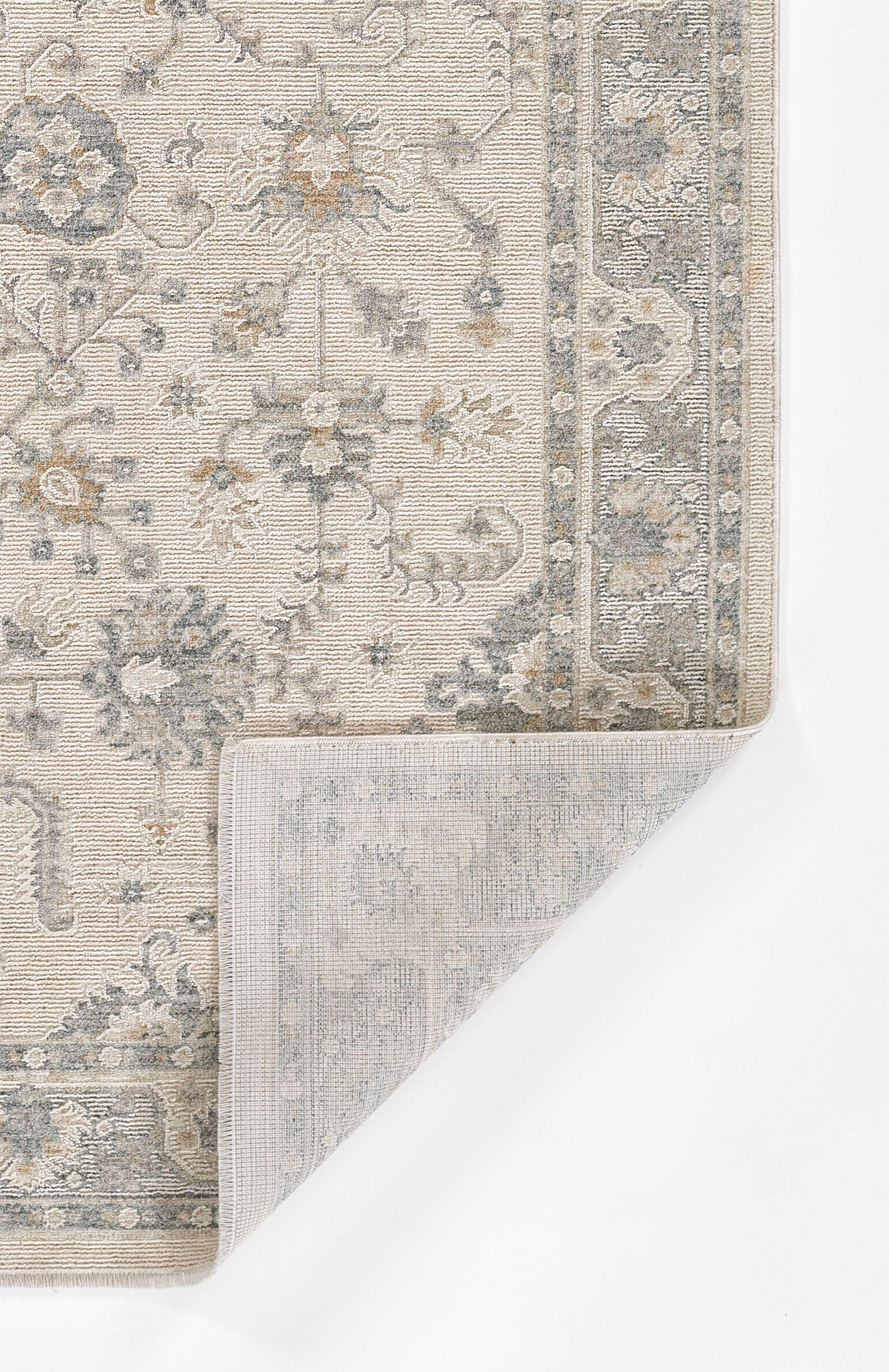 Light blue-gray oriental rug with ivory floral motifs and ornate border; folded corner reveals backing.