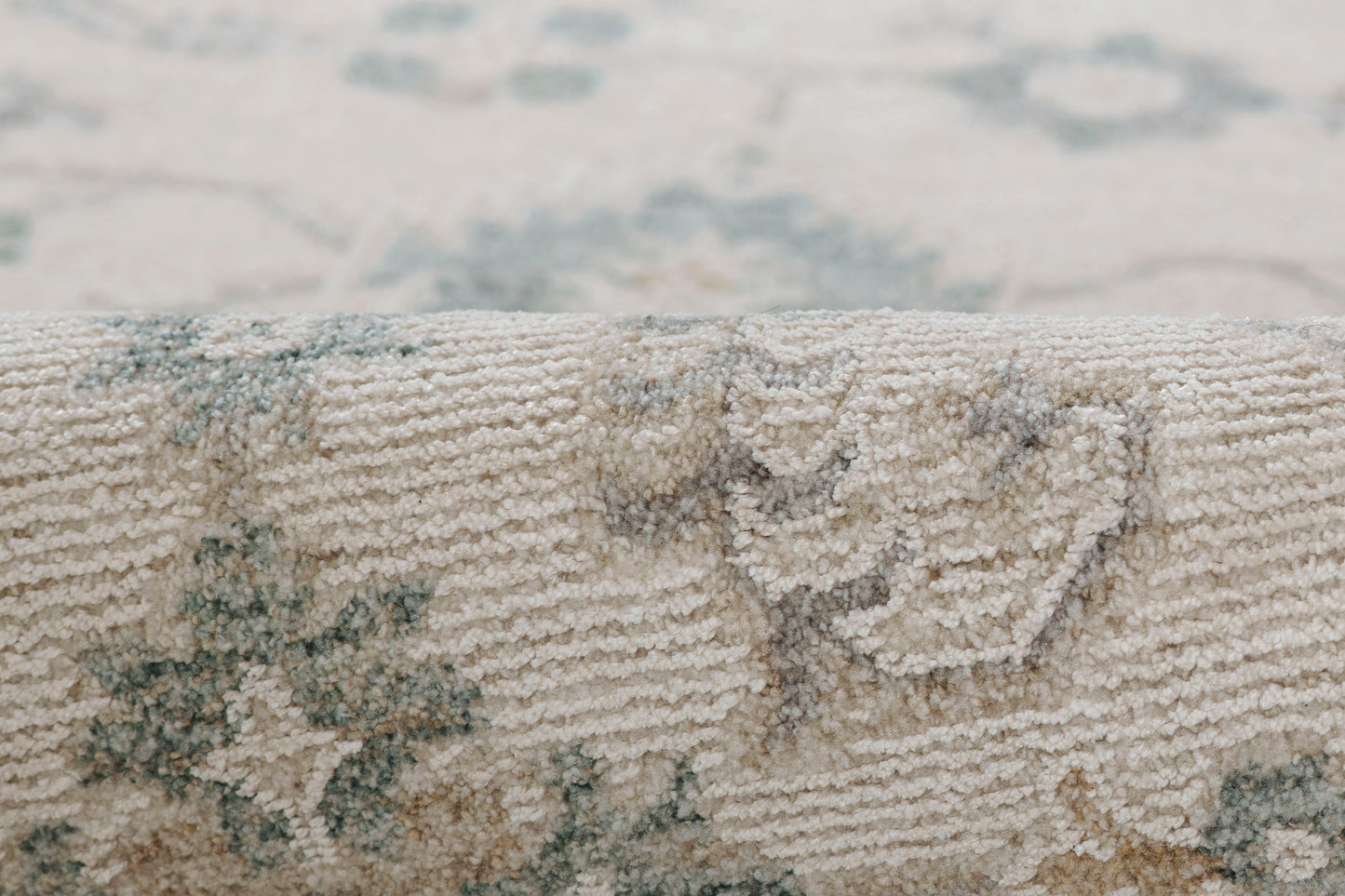 Close-up of a beige woven rug with blue floral medallion pattern and soft textured pile.