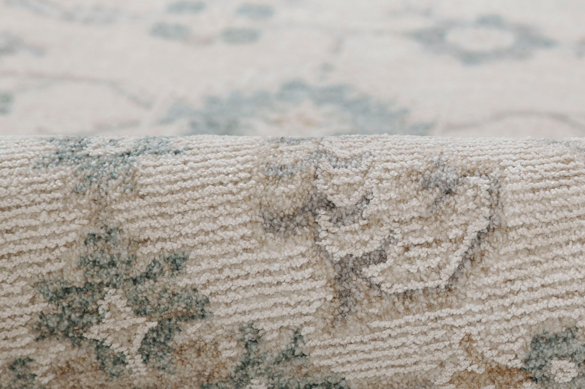 Close-up of a beige woven rug with blue floral medallion pattern and soft textured pile.