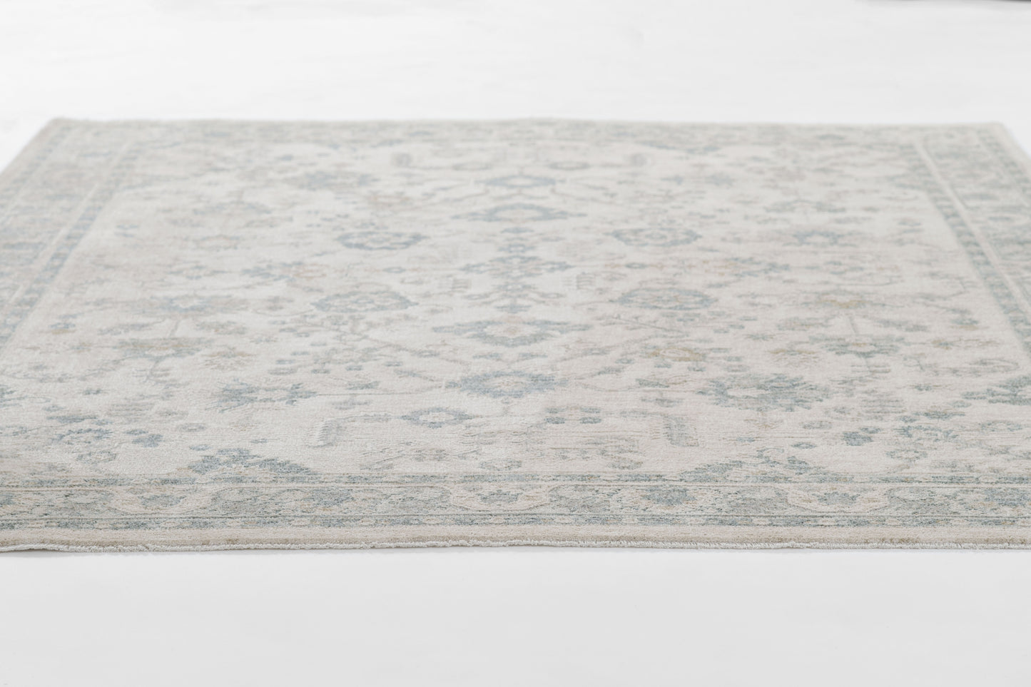 Pale blue and ivory oriental area rug with a subtle geometric floral motif.
