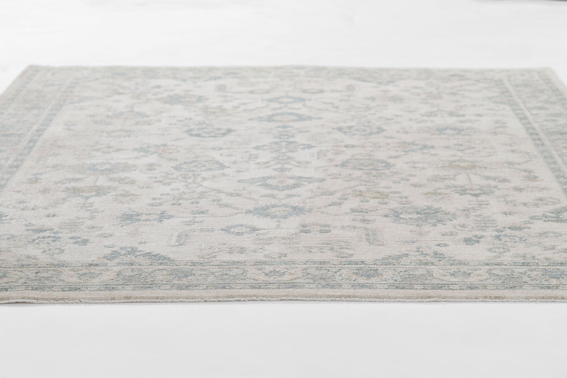 Pale blue and ivory oriental area rug with a subtle geometric floral motif.