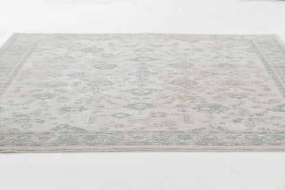 Pale blue and ivory oriental area rug with a subtle geometric floral motif.