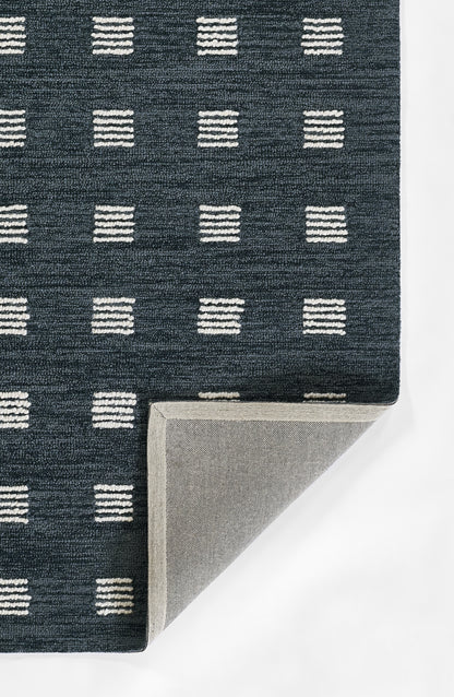 Navy blue woven rug with white stacked-dash square pattern; folded corner reveals light gray underside.
