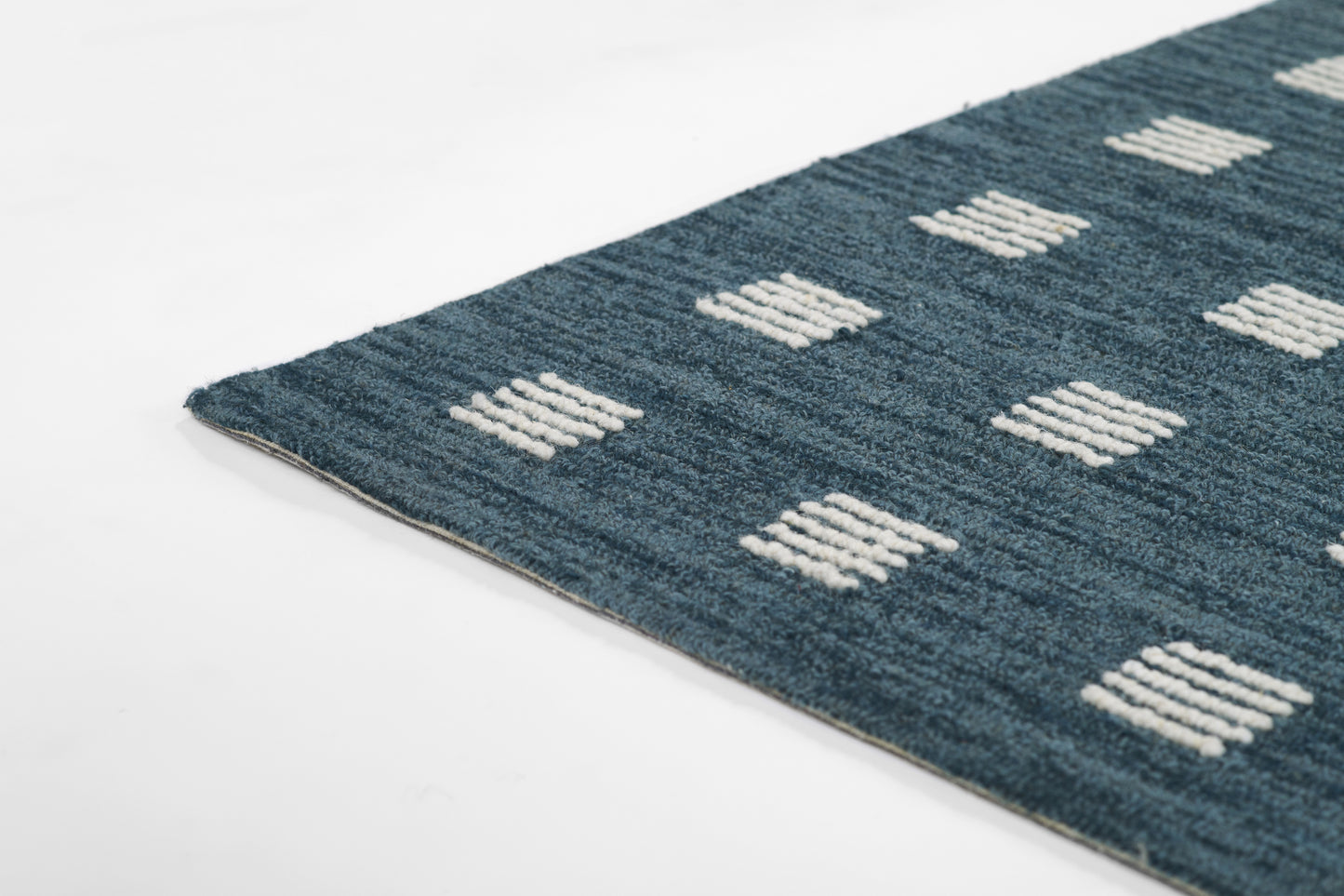 Blue textured area rug with white tufted square grid pattern; corner shown.