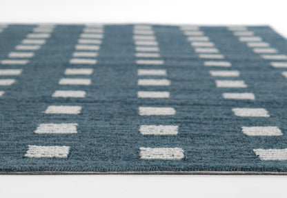 Blue woven area rug with white rectangular dash pattern in vertical rows; low-pile & modern geometric style.