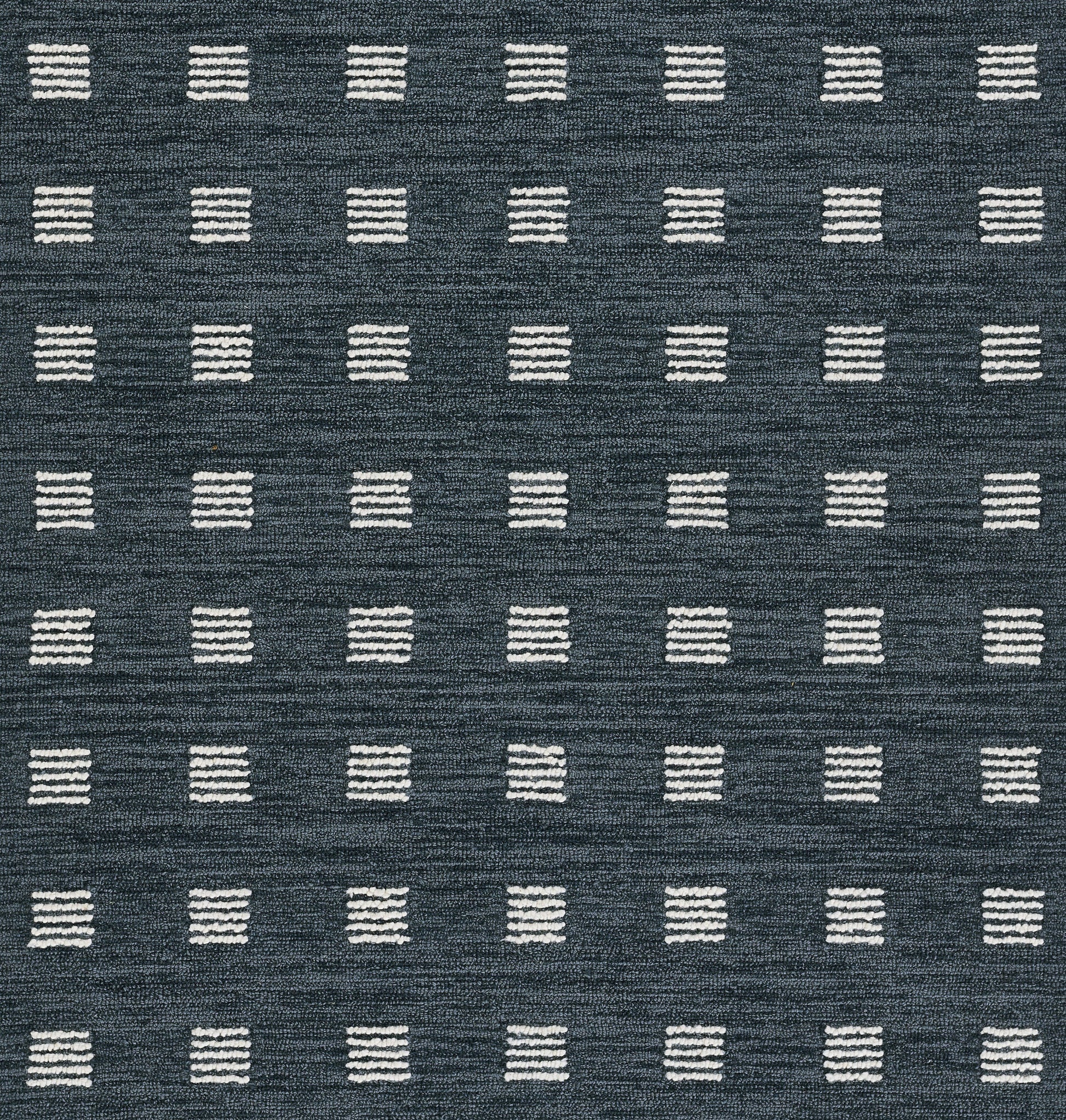 Navy blue rug featuring a grid of small white stitched square blocks in a geometric, modern design.
