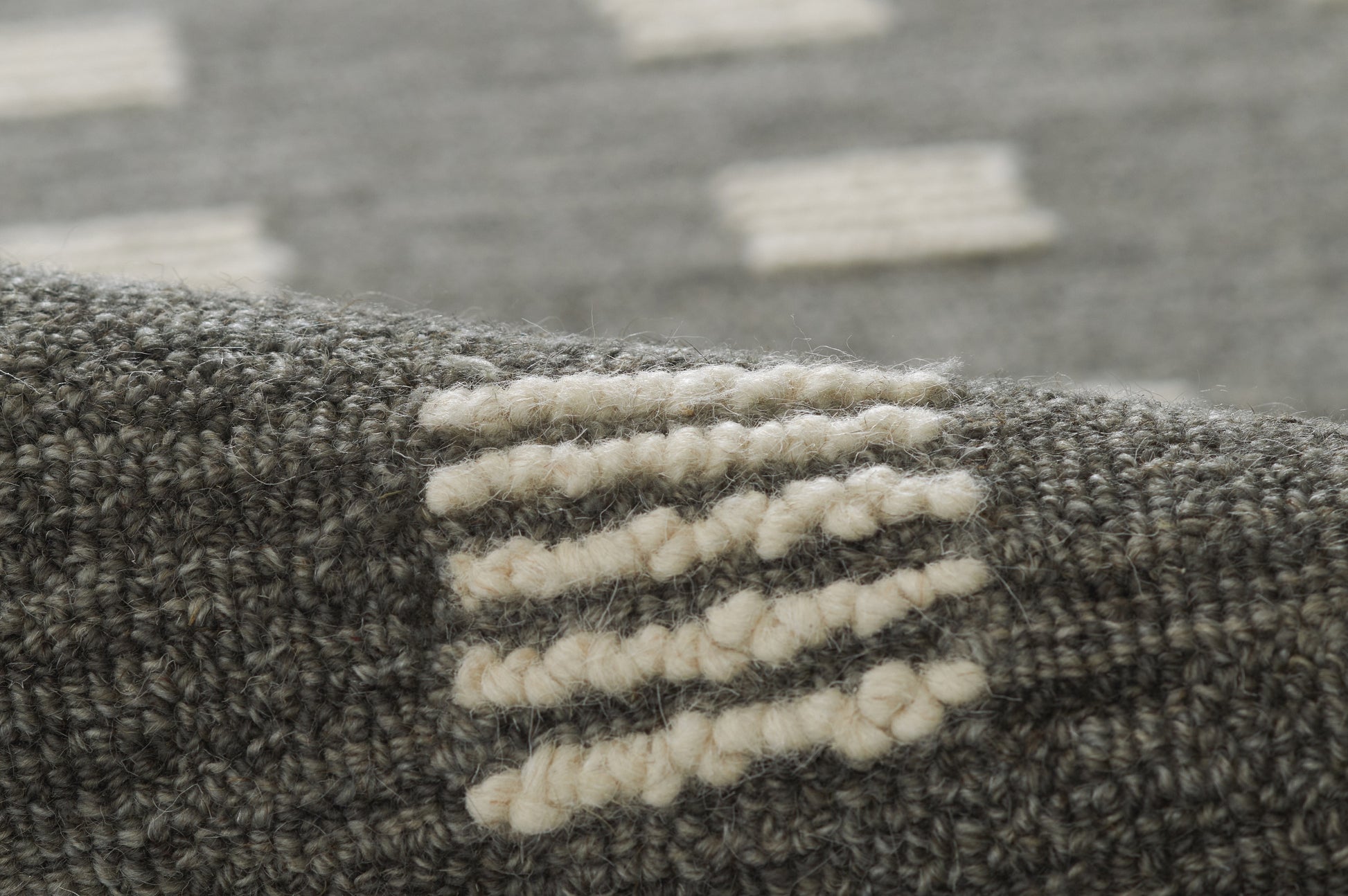 Charcoal gray woven rug with cream boucle yarn accents forming a subtle linear pattern.
