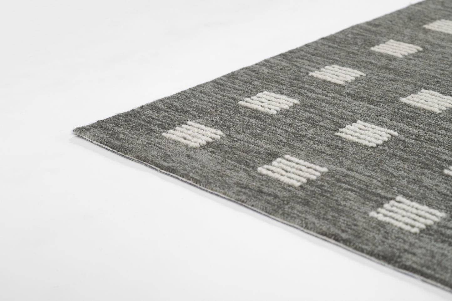 Grey rectangular rug with white tufted square motifs; modern geometric style, soft pile for living room.