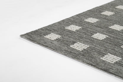 Gray tufted rug with white square geometric blocks; modern rectangular floor covering.