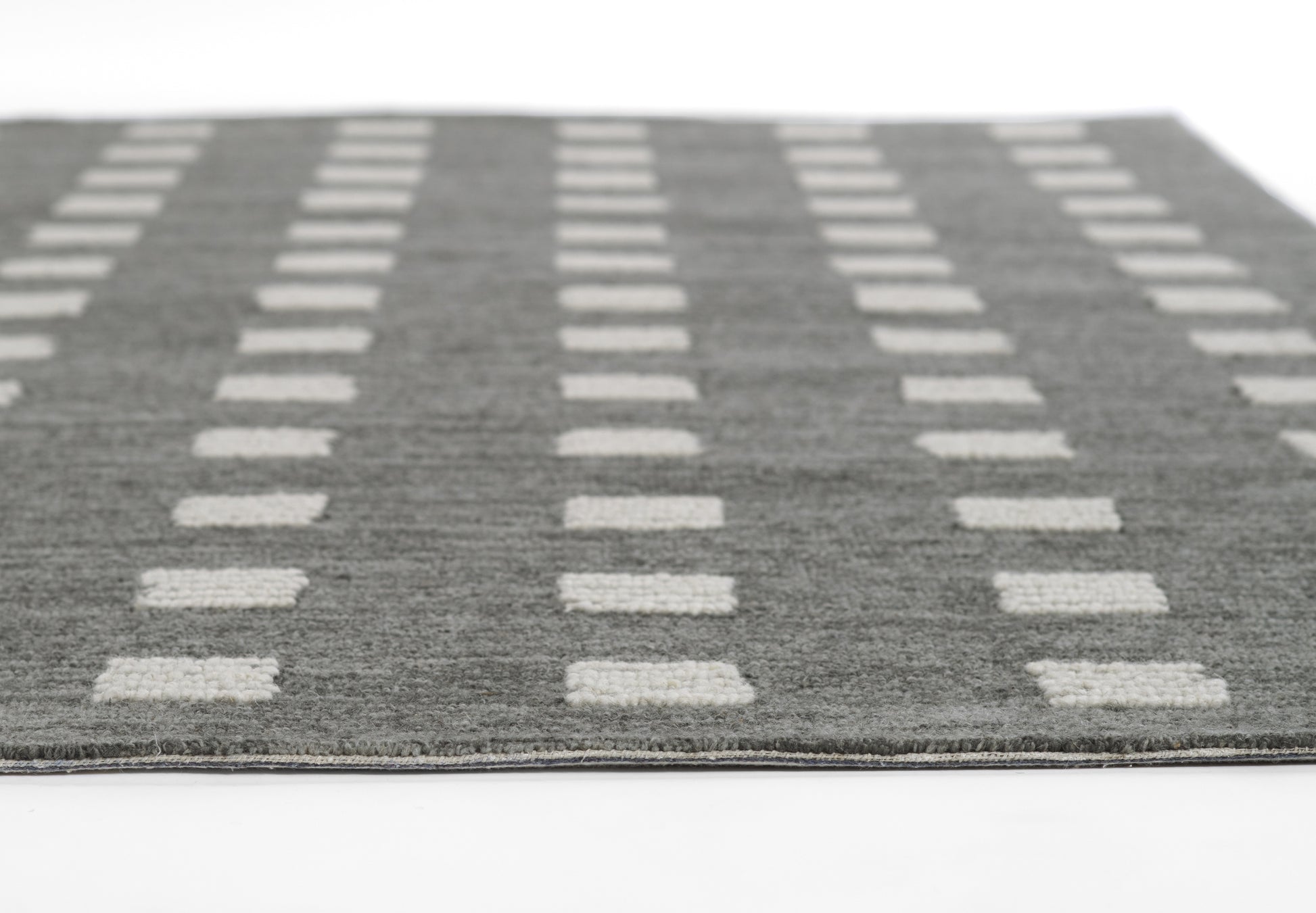 Charcoal gray rug with cream rectangular grid pattern; flat-weave, modern geometric style for living room floors.
