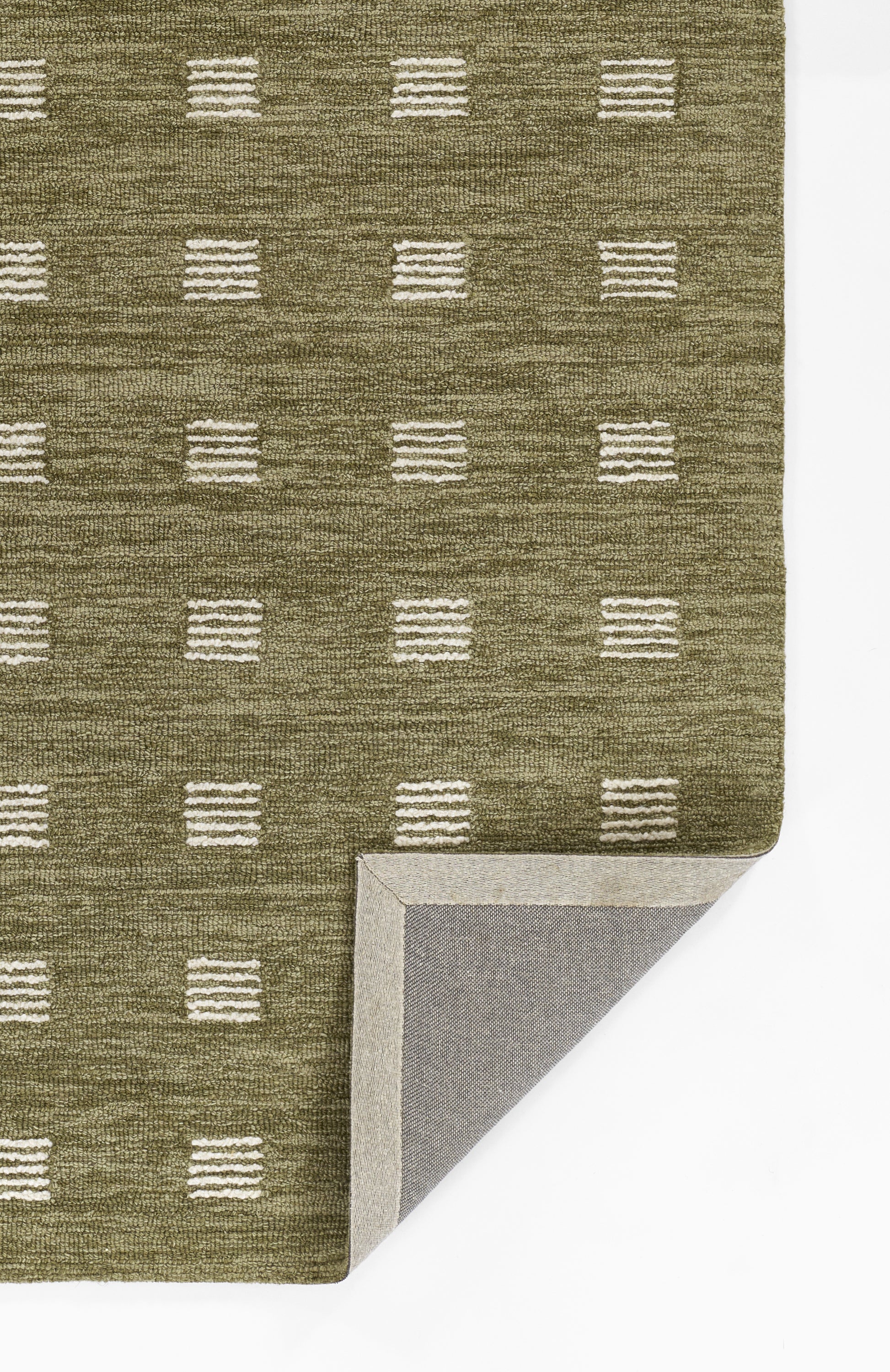 Olive green woven rug with white dashed square pattern; folded corner reveals gray backing, contemporary geometric style.