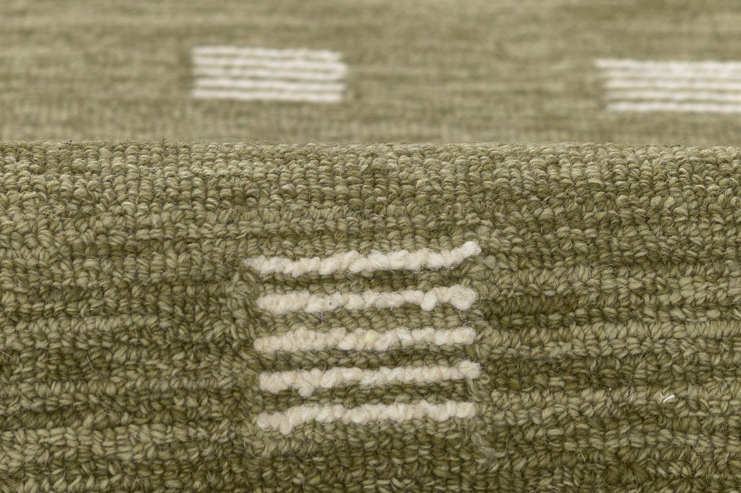 Olive green textured rug with white dash stripe motifs; looped pile, geometric modern pattern.