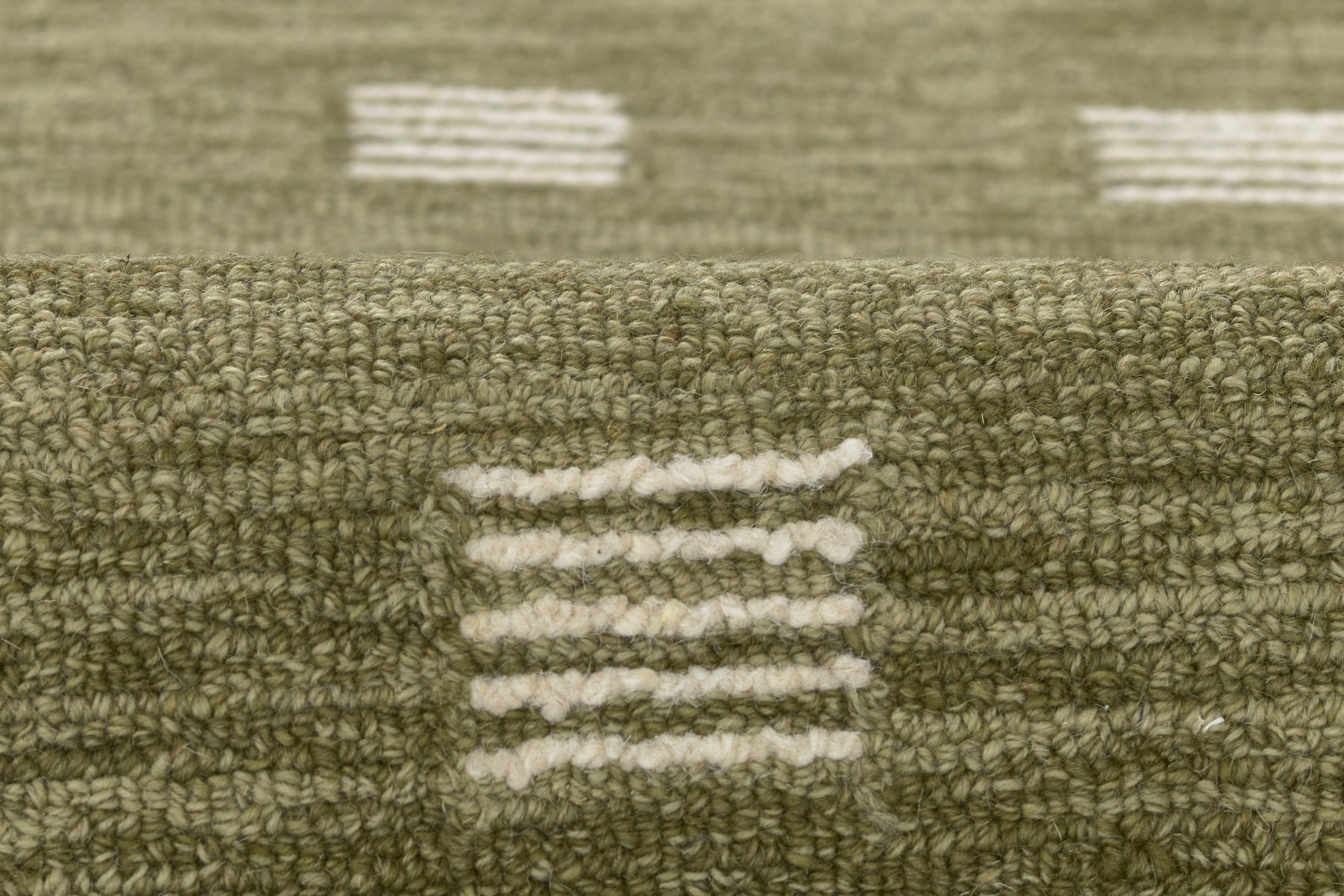 Olive green textured rug with white dash stripe motifs; looped pile, geometric modern pattern.