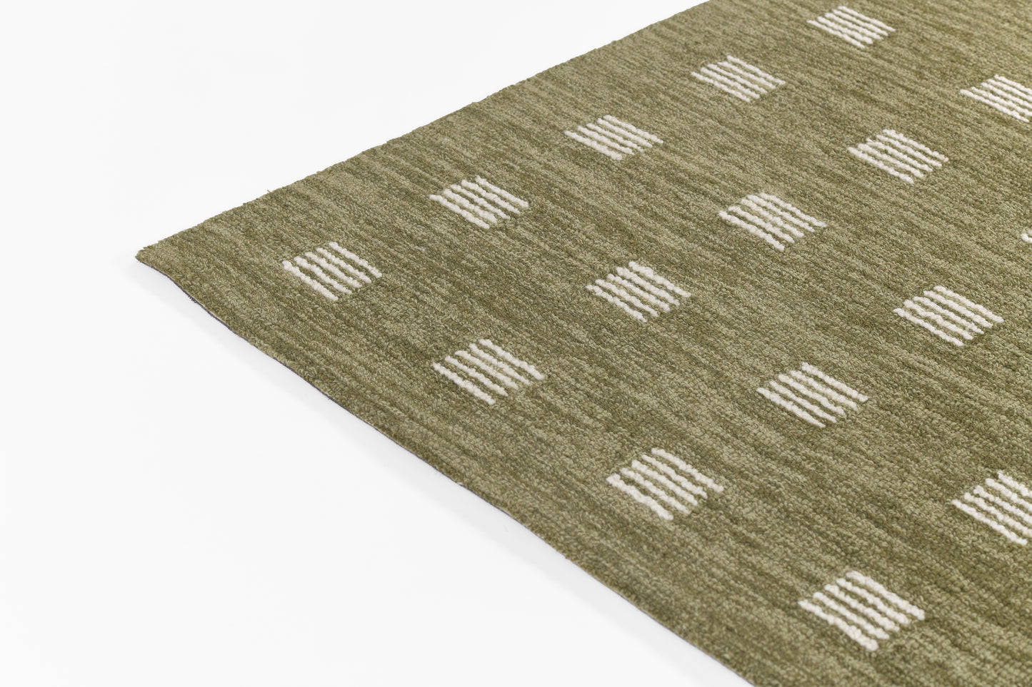 Olive green flat-weave rug with white stitched square blocks in a grid pattern.