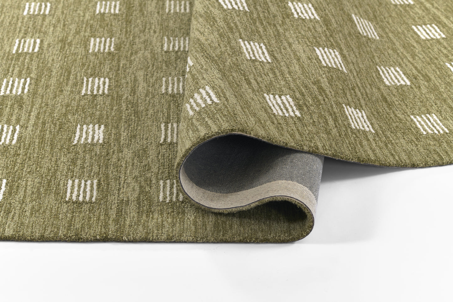 Olive green rug with white dashed square pattern, partially rolled to reveal grey underside; contemporary geometric style.