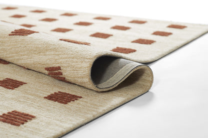Beige rug with brown square motifs, soft pile, rolled edge showing gray backing.