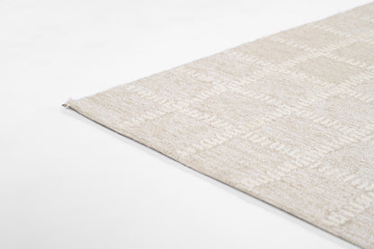 Beige textured area rug with cream geometric pattern, corner view against a white surface.