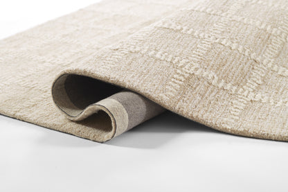 Beige patterned area rug with subtle geometric texture and medium plush pile, edge rolled to reveal gray backing.
