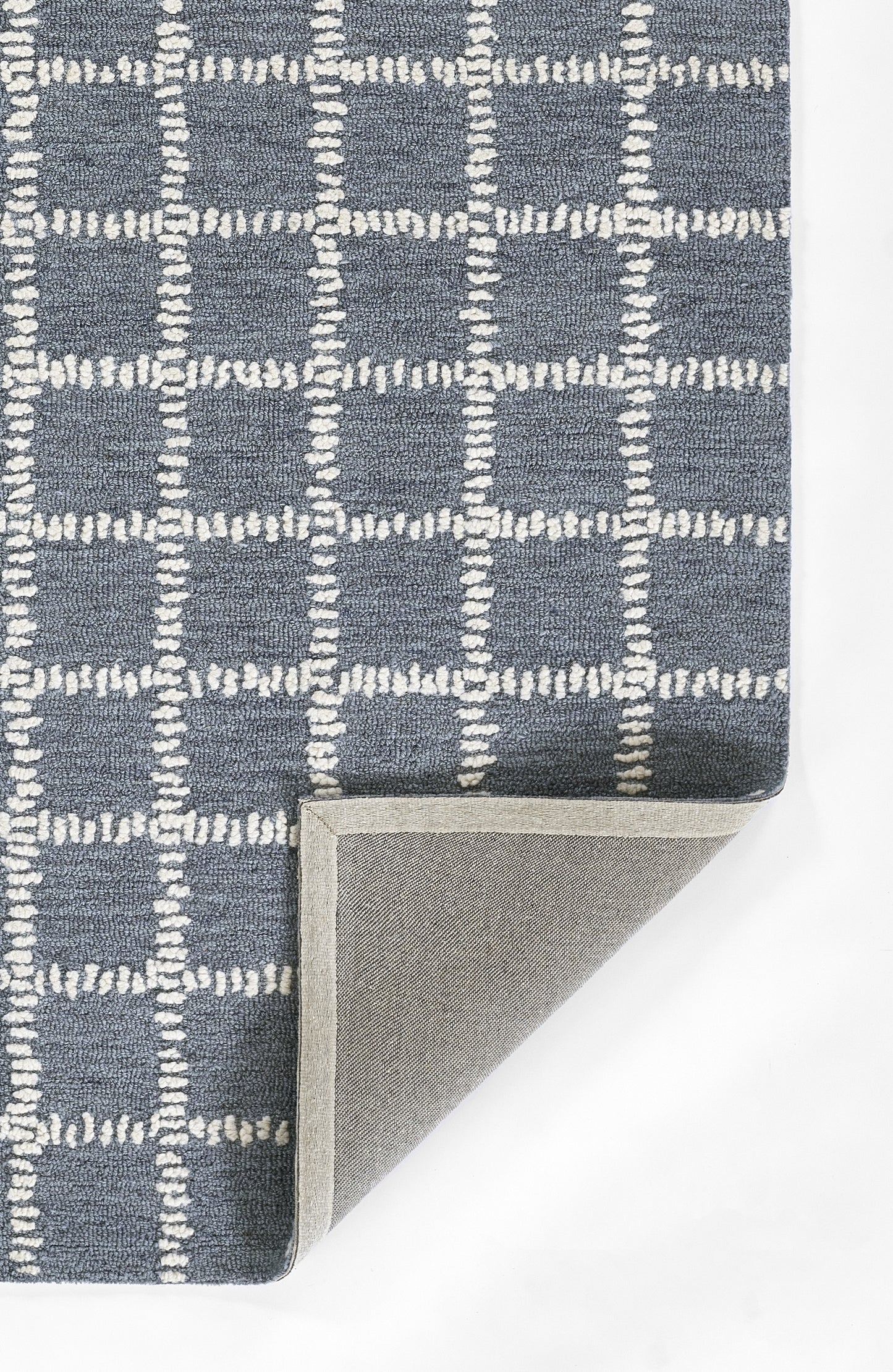 Blue-gray rug with white stitched grid pattern; checkered squares, folded corner shows light gray underside.