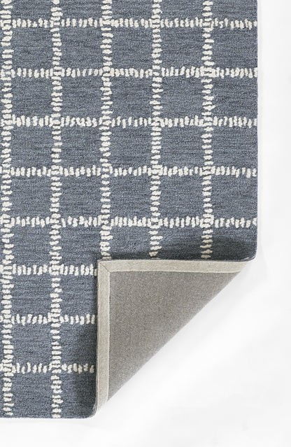 Blue-gray rug with white stitched grid pattern; checkered squares, folded corner shows light gray underside.