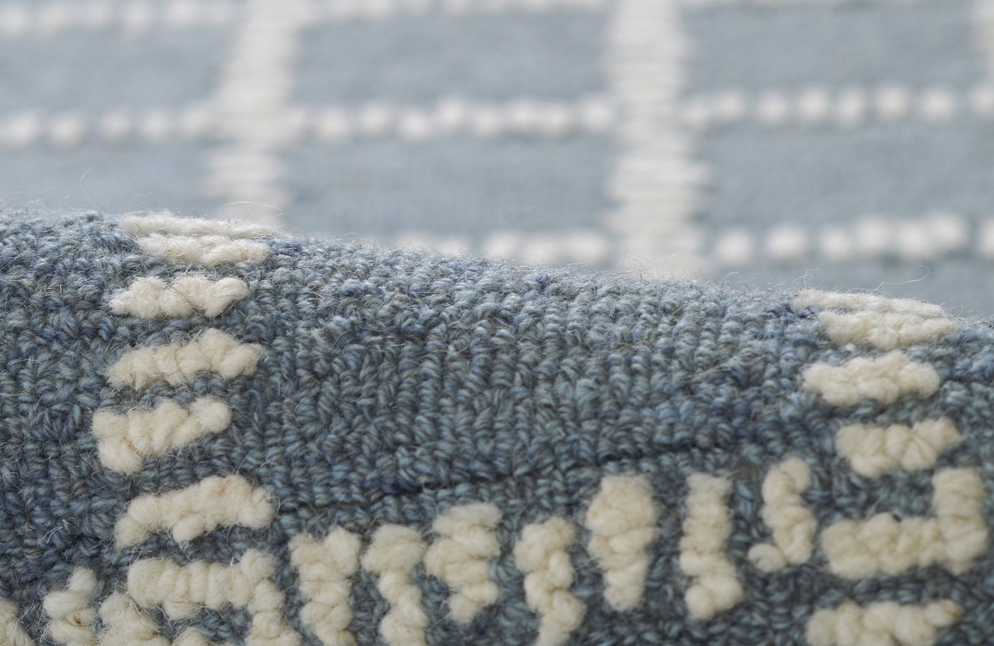 Blue-gray woven rug with cream tufted motifs and dense texture for living room floor decor.