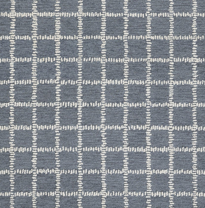Blue-gray woven rug with white stitched grid squares in a modern geometric pattern.