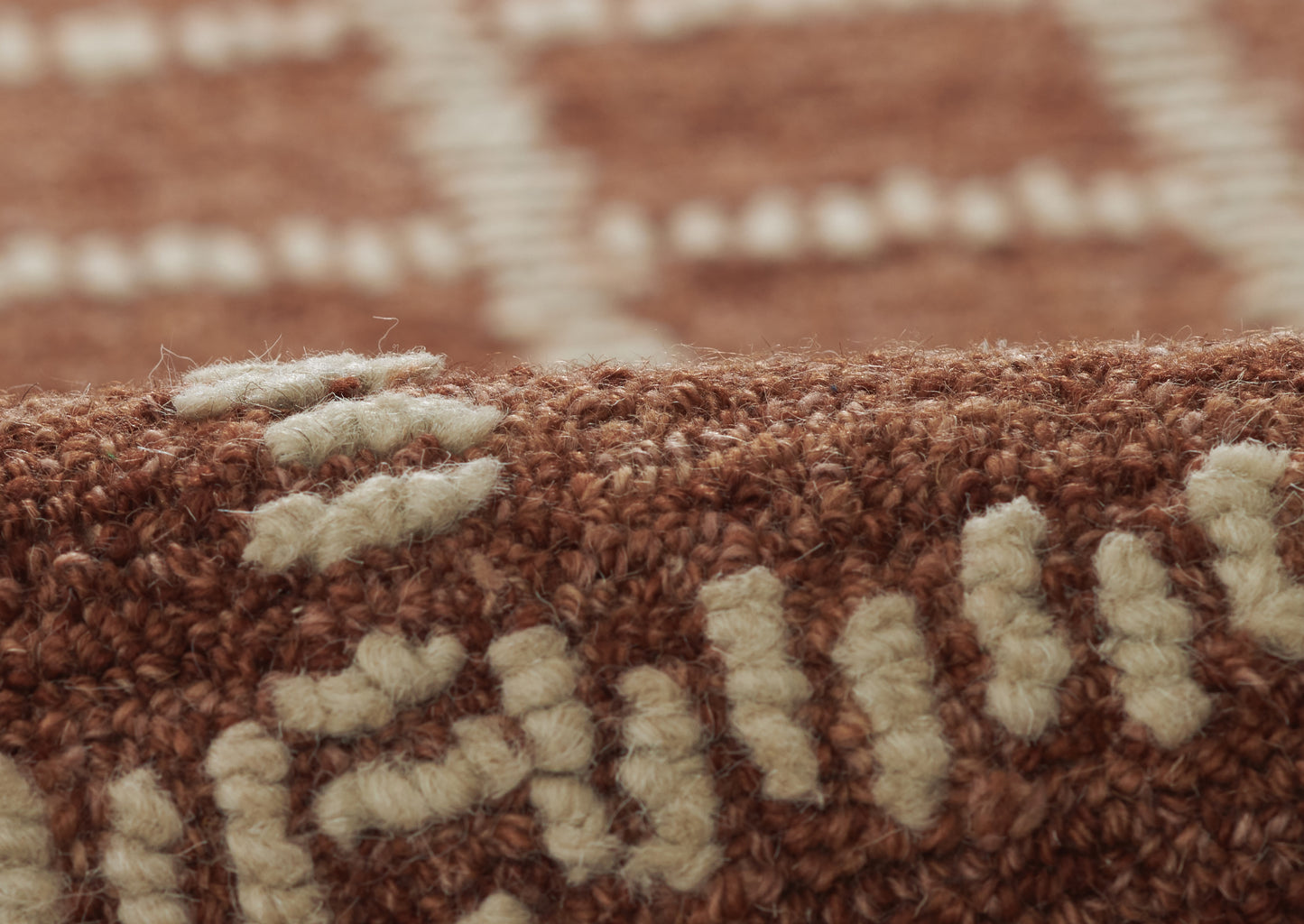 Close-up of brown woven rug with cream tufted pattern; rustic wool texture for floor decor.