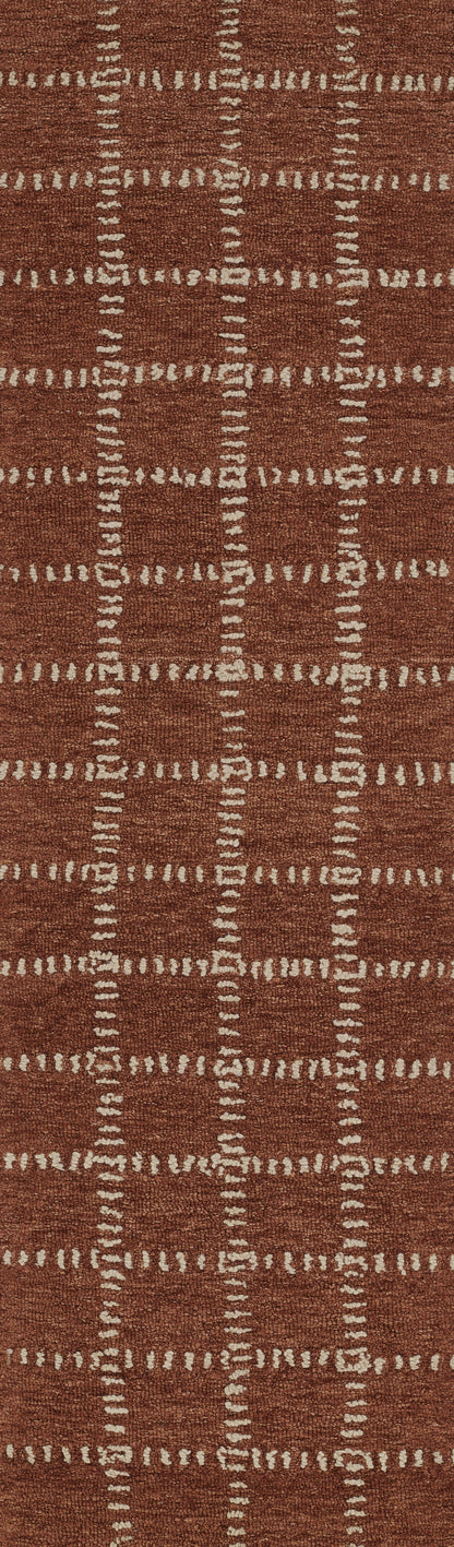Rust-orange rectangular woven rug with cream dashed grid pattern and textured surface.