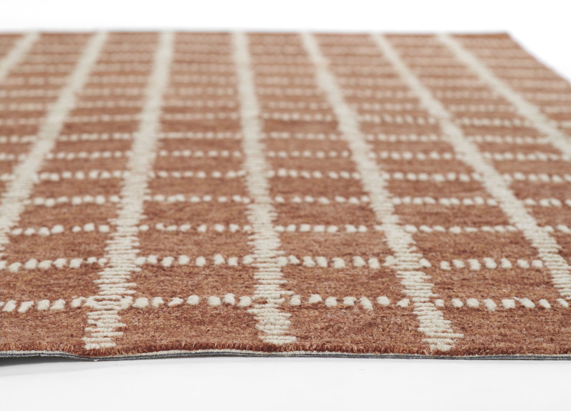 Brown rug with white dotted grid pattern and soft textured pile, close-up view.