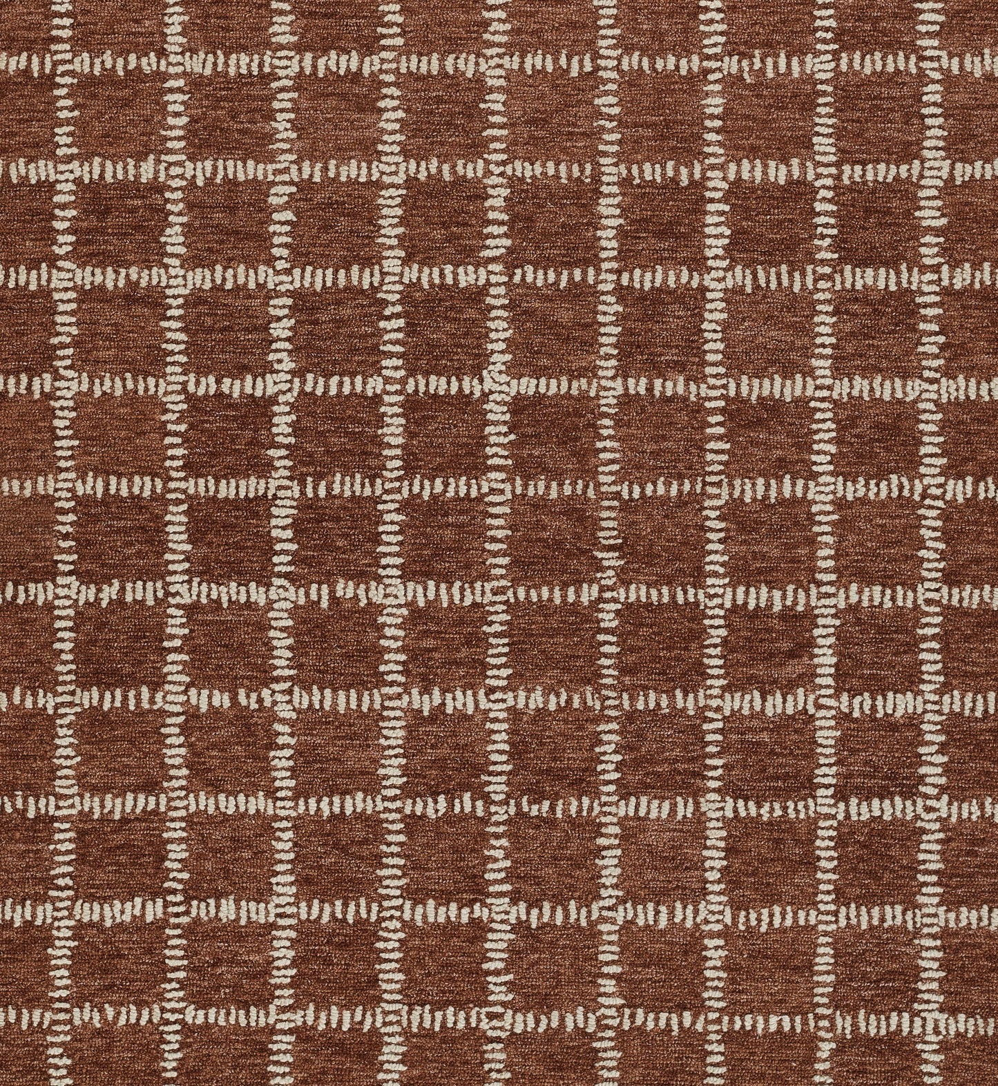 Rust-brown woven rug with cream dashed grid squares; geometric, modern pattern for a warm living room.