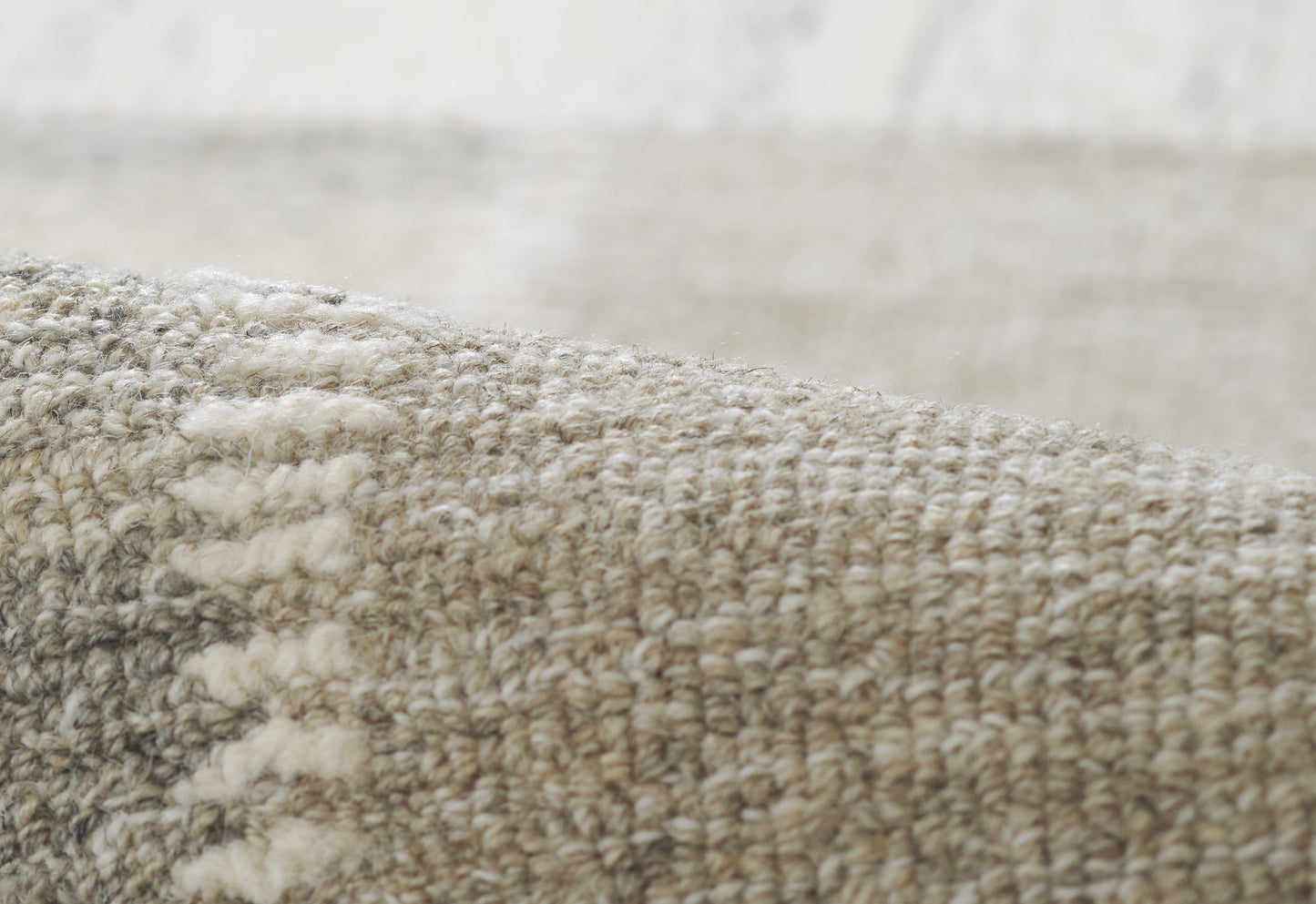 Close-up of a gray-beige woven rug with a chunky loop pile, soft neutral texture for living room decor.