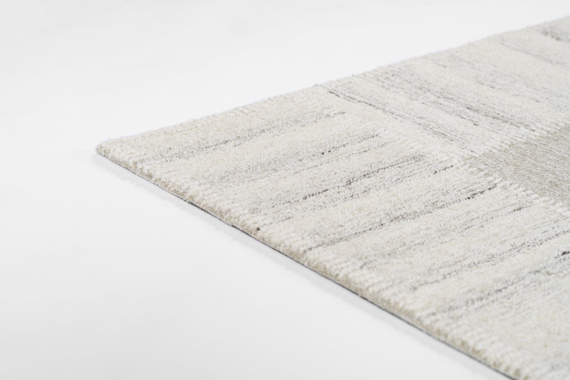 Neutral-toned striped area rug in cream and gray with plush pile, close-up corner.