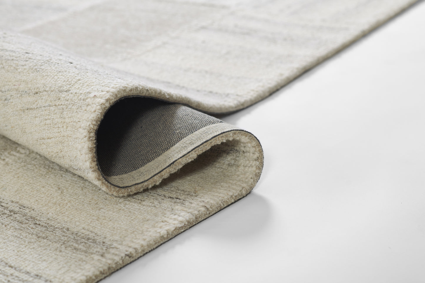Beige-gray plush area rug with rolled edge, soft high-pile texture, modern rectangular living-room rug.