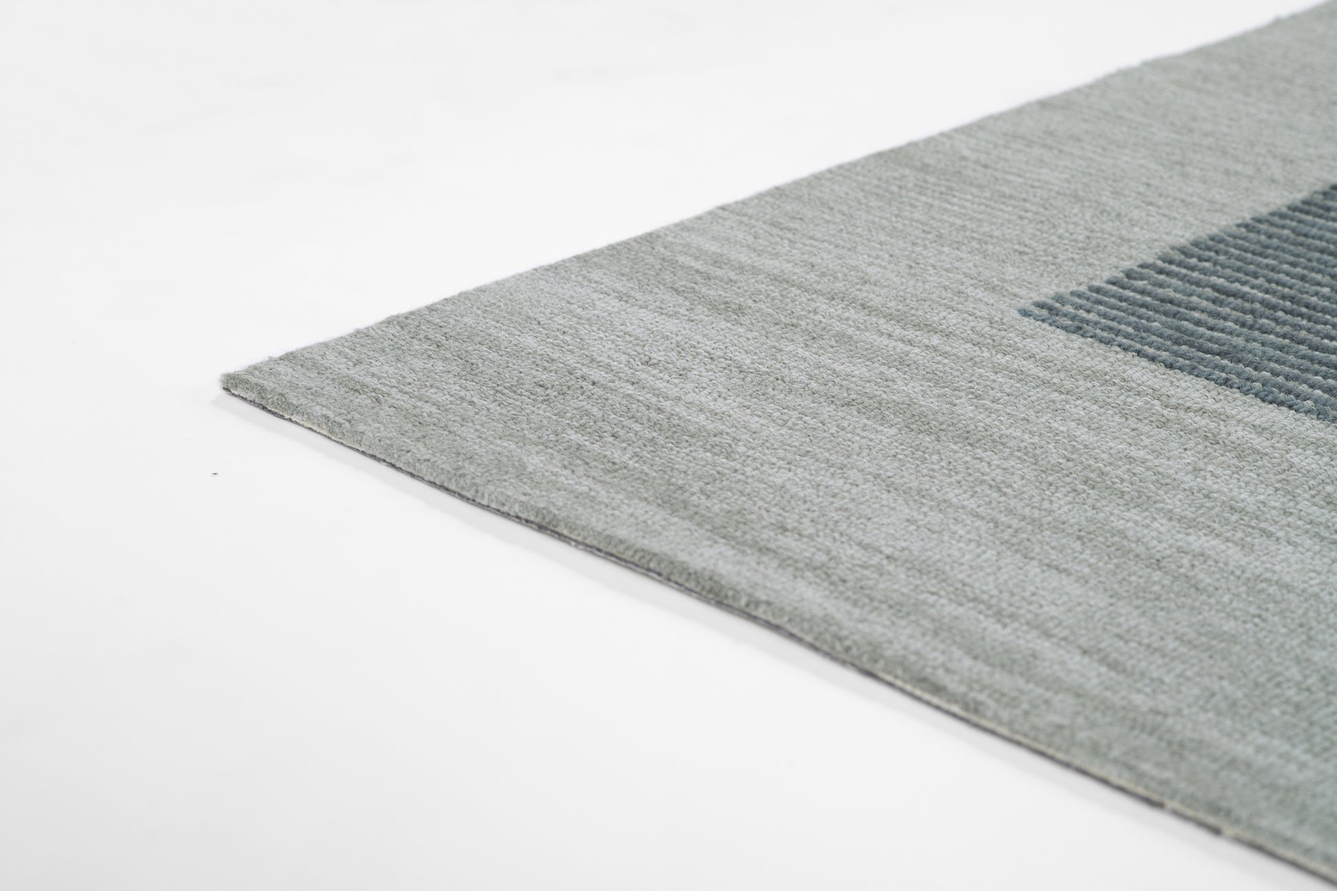 Rectangular rug with light gray base and dark blue square motif; plush soft pile, edge visible.