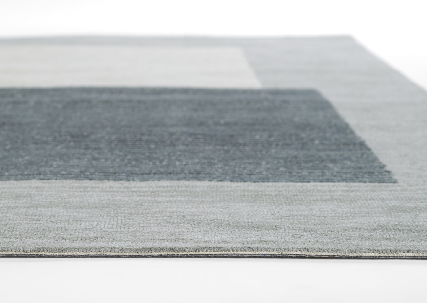 Rectangular area rug with gray and blue color-blocked geometric pattern and textured weave.