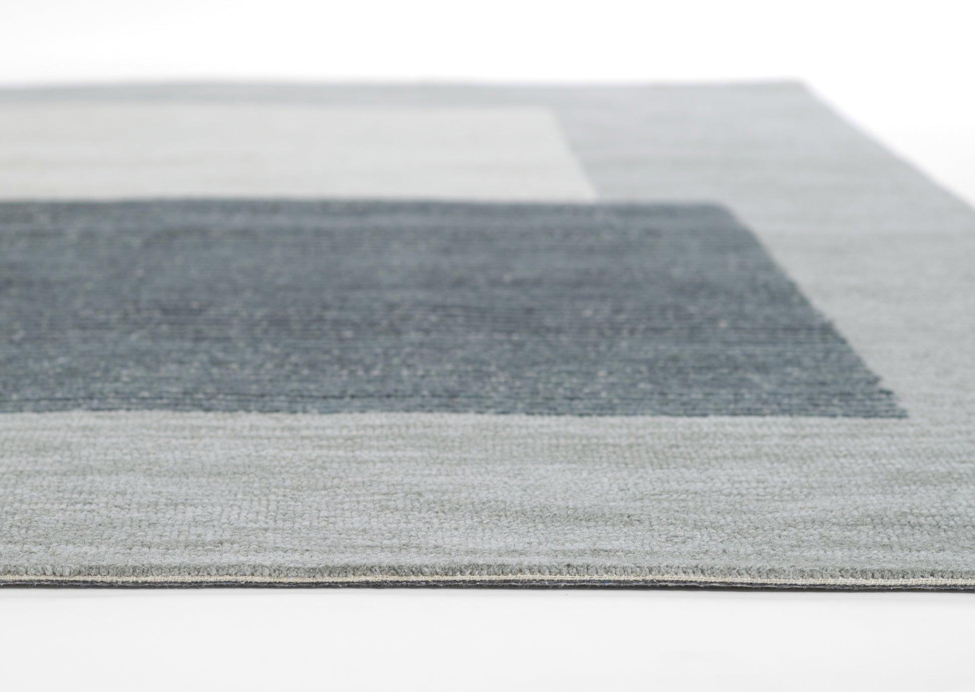 Rectangular area rug with gray and blue color-blocked geometric pattern and textured weave.
