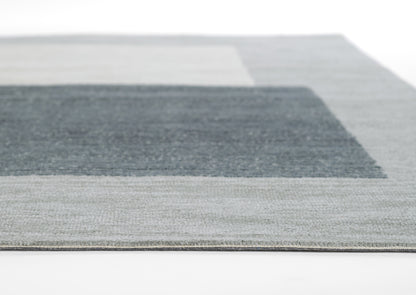 Rectangular area rug with gray and blue color-blocked geometric pattern and textured weave.