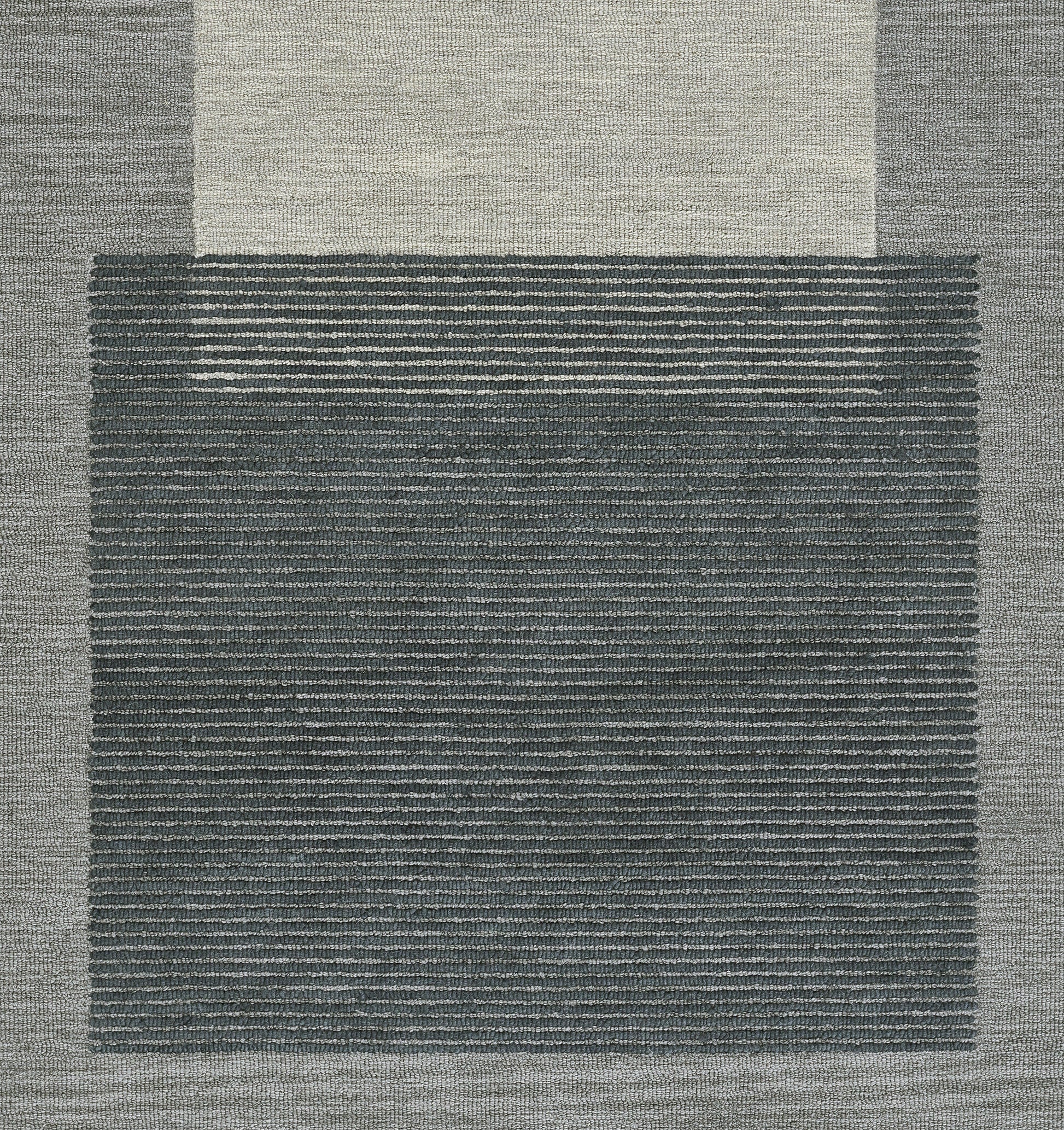 Blue-gray area rug with a dark striped central panel and light beige outer border; modern geometric, textured weave.