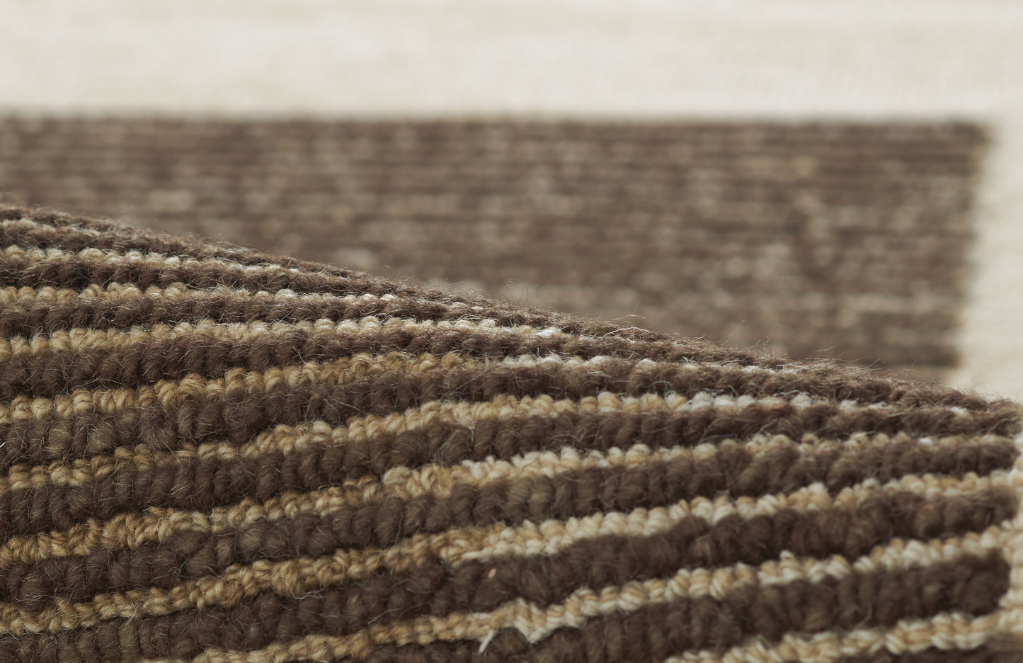 Brown and beige striped braided rug with chunky wool texture and rolled edge.