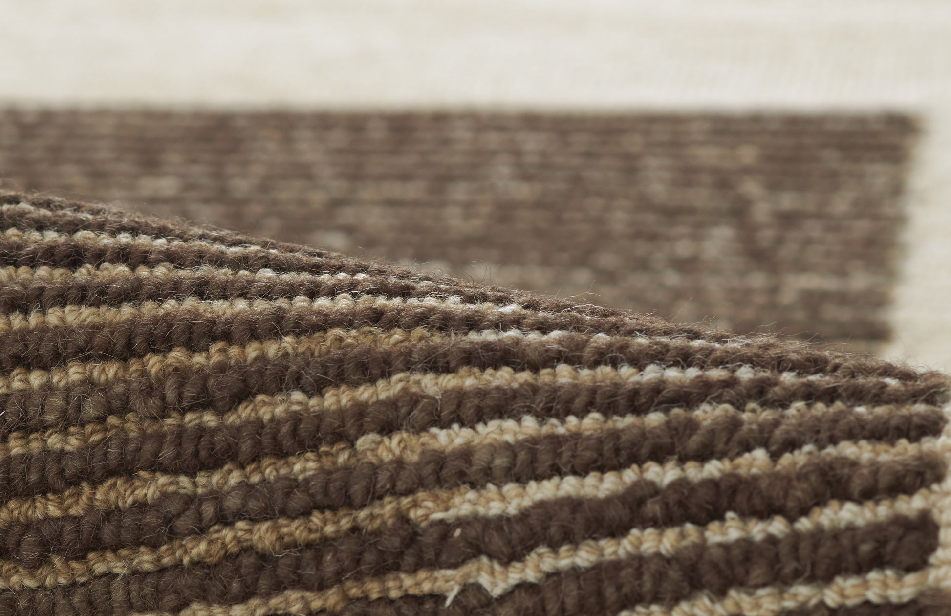 Brown and beige striped braided rug with chunky wool texture and rolled edge.