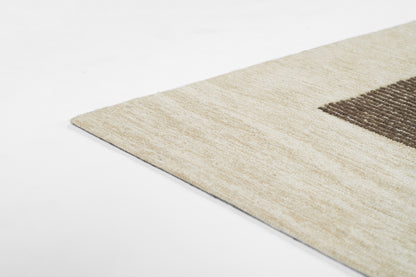 Beige rectangular area rug with a dark brown geometric block, soft textured pile, ideal for living room decor.